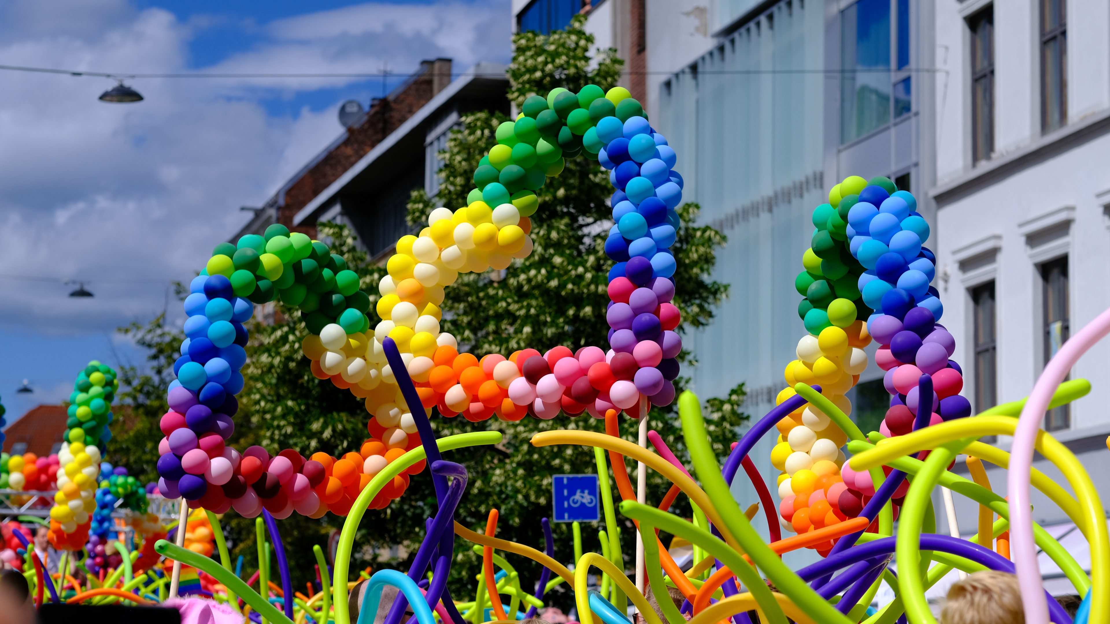 Tre ballonghjerter i regnbuens farger under pride-paraden.